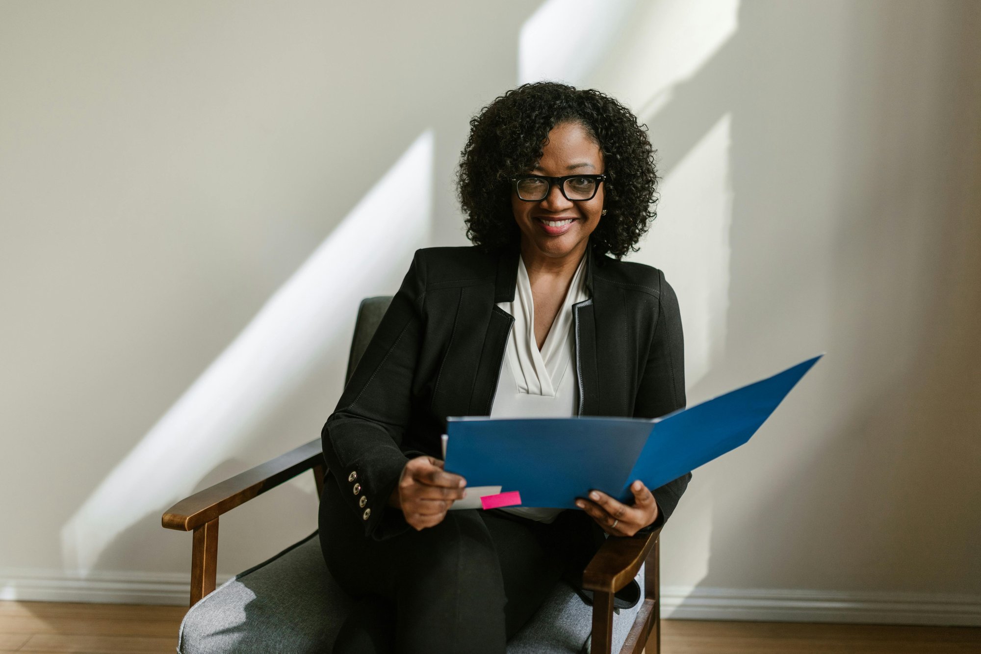 Business dressed woman sat in armchair holding a folder open