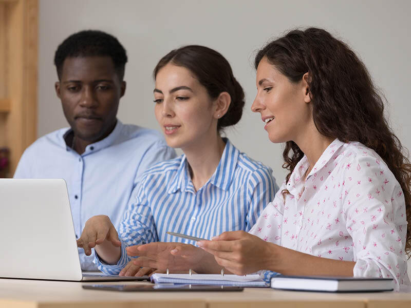 Three teachers together in front of laptop.