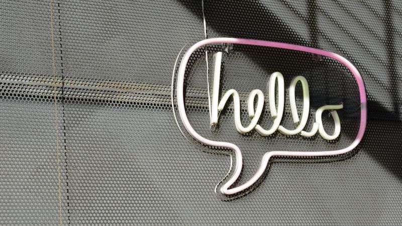 A neon sign with the words hello in a speech bubble, mounted on a wall