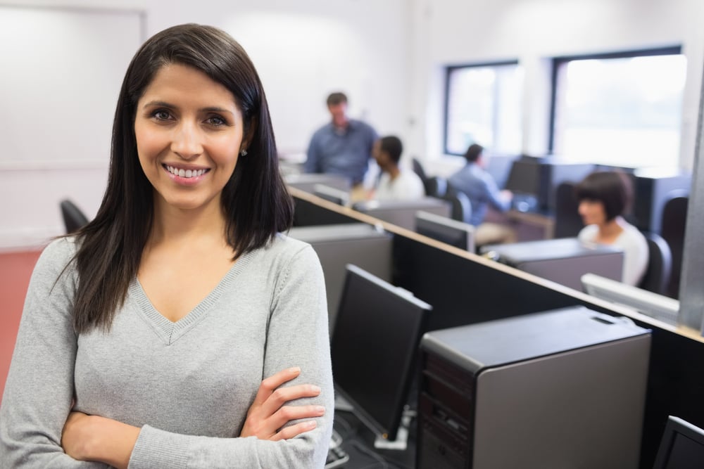 Woman smiling and standing in the front of the computer class