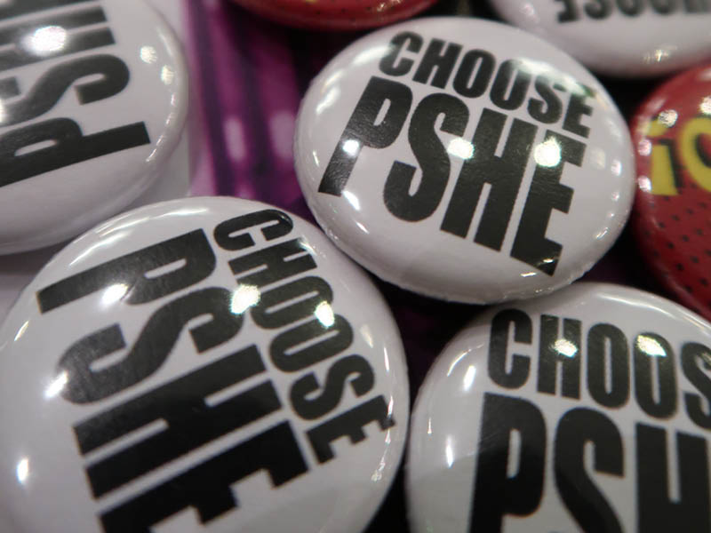 A close-up of badges that read 'choose PSHE'